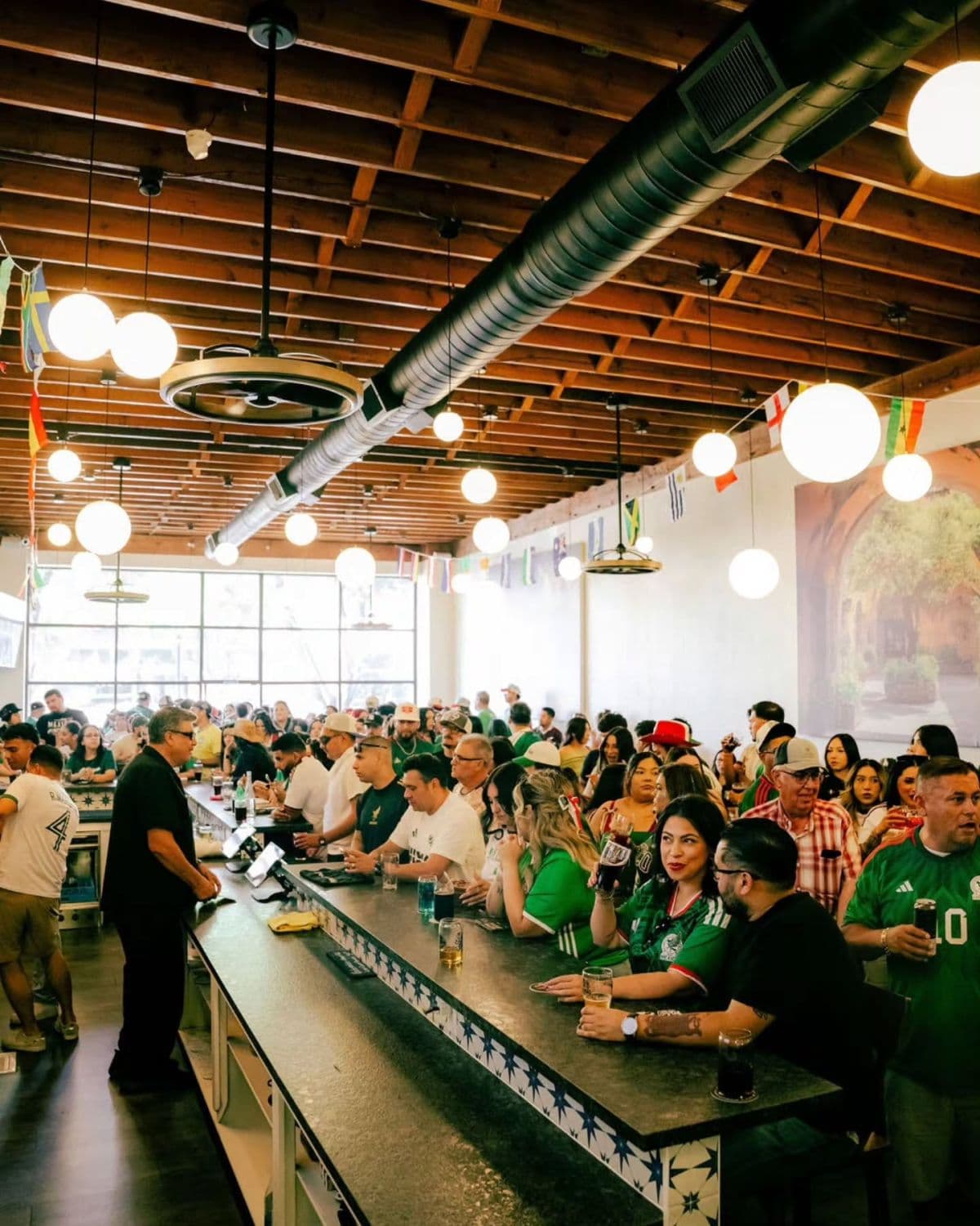 The long bar packed with fans in green on a match day.